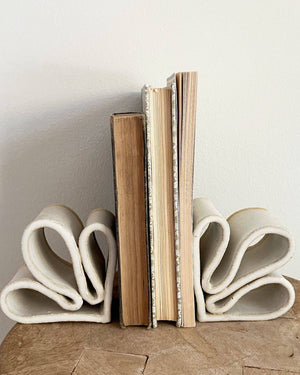 Ceramic bookends holding books on a wooden surface with a neutral background