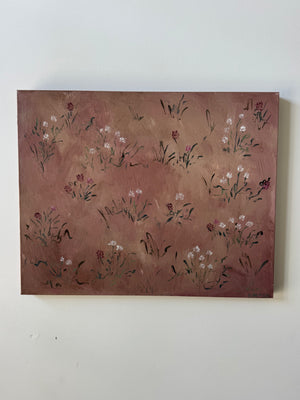 A rectangular canvas painting featuring delicate hand-painted wildflowers in white, pink, and green on a textured, warm reddish-brown background, hung on a plain off-white wall.