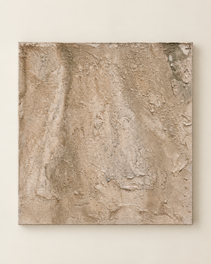 An abstract square canvas painting with a heavily textured, impasto surface in warm beige, tan, and light brown tones, mounted on a light beige wall.